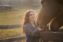 Donna accarezzando i musi di due cavalli — Foto stock