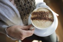Femme tenant une tasse pleine de cappuccino — Photo de stock