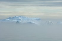 Iceberg y masa de tierra frente a la bahía de Baffin - foto de stock