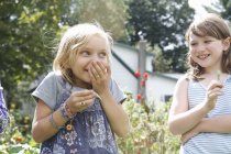 Children standing outdoors in a garden laughing. — Stock Photo
