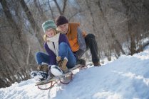 Man pushing woman from the top of a slope on a toboggan. — Stock Photo