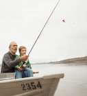 Мужчина показывает мальчику, как ловить рыбу — стоковое фото