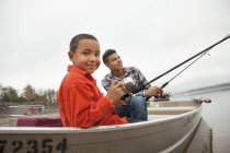 Dos chicos pescando desde un barco . - foto de stock