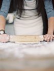 Женщина разворачивает тесто на столешнице — стоковое фото