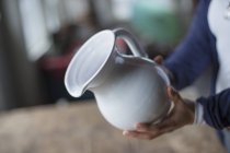 Woman holding a white pottery jug — Stock Photo