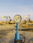 Air pressure gauge, oil rigs in background — Stock Photo