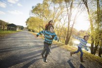 Woman and children running by a lake — Stock Photo