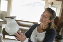Mulher segurando um jarro de cerâmica branca — Fotografia de Stock