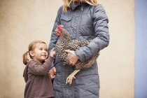 Young girl and woman holding chicken — Stock Photo