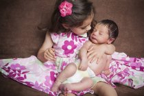 Маленькая девочка держит новорожденного ребенка — стоковое фото