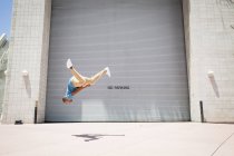 Man somersaulting in front of a garage door. — Stock Photo