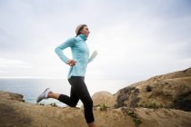 Frau joggt an der Küste entlang. — Stockfoto