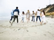 Männer und Frauen laufen am Strand — Stockfoto