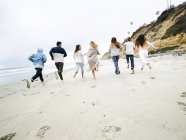 Hommes et femmes qui courent sur une plage — Photo de stock
