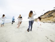 Hommes et femmes qui courent sur une plage — Photo de stock