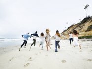 Uomini e donne che corrono su una spiaggia — Foto stock