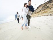 Hombres y mujeres corriendo en una playa - foto de stock