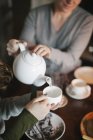 Mulher derramando chá de um bule de chá — Fotografia de Stock