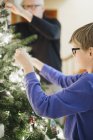 Man and boy decorating a Christmas tree — Stock Photo