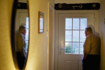 Homem idoso em pé por uma porta — Fotografia de Stock