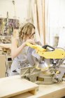Woman woodworker using a mechanical saw — Stock Photo