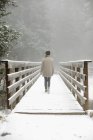 Жінка ходить на пішохідному мосту в снігу . — стокове фото