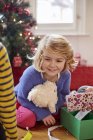 Chica en el día de Navidad desenvolver regalos - foto de stock