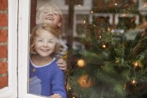 Children looking out of a window — Stock Photo
