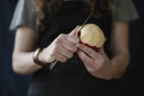 Frau schält mit Messer einen Apfel. — Stockfoto