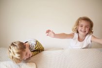Children playing behind a sofa — Stock Photo