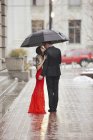 Coppia baciarsi sotto un ombrello su una strada
. — Foto stock