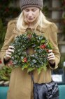 Woman carrying a christmas wreath — Stock Photo