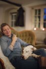 Жінка сидить на дивані з собакою — стокове фото