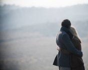 Пара, обнимающаяся в поле в стране — стоковое фото