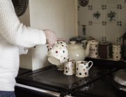 Mains féminines verser le thé dans la tasse — Photo de stock