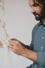 Male artist stitching and weaving with thread. — Stock Photo