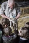 Фермер и дети с новорожденной бараниной — стоковое фото
