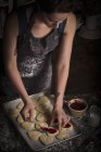 Donna che diffonde marmellata di lamponi sui biscotti — Foto stock