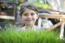 Girl standing smiling by glasshouse bench — Stock Photo