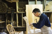 Homem trabalhando em uma cadeira de madeira . — Fotografia de Stock