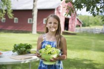 Girl carrying a large bowl of apples. — Stock Photo