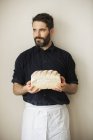 Baker holding a loaf of white bread. — Stock Photo