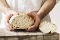 Panettiere con in mano un pane. — Foto stock