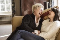 Жінки сидять в дивані і сміються — стокове фото