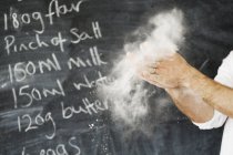 Baker dusting his hands with flour. — Stock Photo