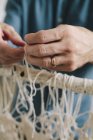 Male artist knotting and weaving threads. — Stock Photo