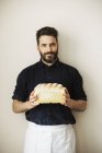 Baker holding a white bread. — Stock Photo