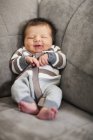 Bebê apoiado no canto do sofá — Fotografia de Stock
