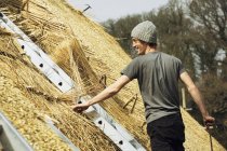 Young man thatching roof — Stock Photo