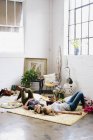 Mujeres tumbadas en el suelo con cojines y posesiones personales - foto de stock